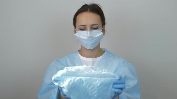 Female doctor puts on medical cap before surgical treatment in clinic wearing mask and latex gloves
