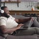 Side View African American Man Entrepreneur Wearing Headphones Talking Video Call at Home Lying on - VideoHive Item for Sale