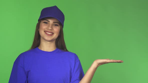 Gorgeous Female Worker in a Baseball Cap and T-shirt Presenting Copyspace