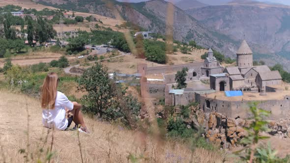 A girl is sitting against the background of mountains in Armenia