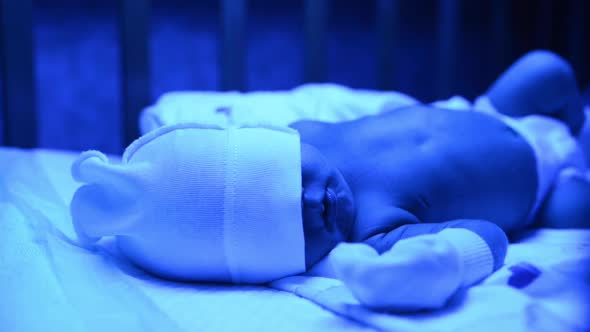 Newborn Having a Treatment for Jaundice Under Ultraviolet Lamp in Home Bed