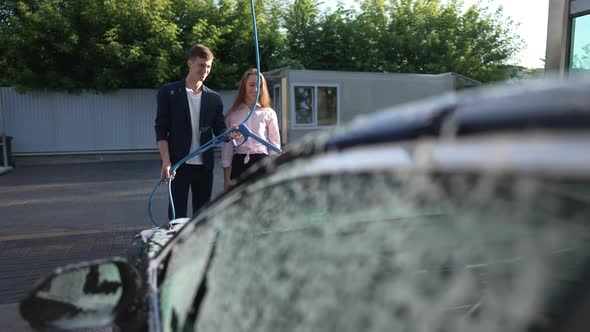 Happy Smiling Couple Standing in Sunshine Washing Car at Wash Station in Slow Motion