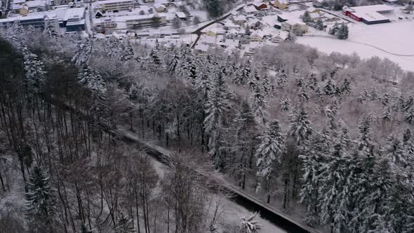 Aerial view of a street in a winter landscape, the street is leading down to a city.