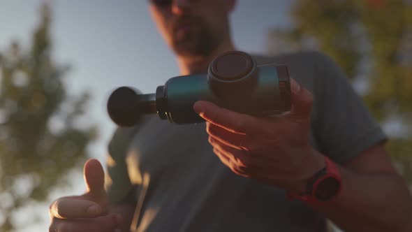 An Athlete Massages with a Percussion Therapy Gun to Relieve the Pain of Muscle Aches After a