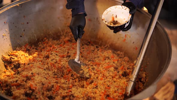 Ready Uzbek Pilaf is Poured Into a Deep Plate with a Slotted Spoon