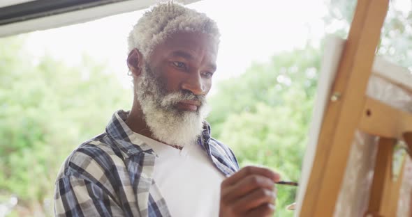 Video of african american senior man painting picture outside