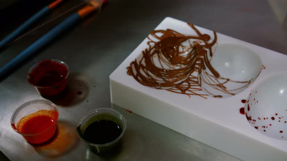 Worker painting a chocolate mould using colored chocolate