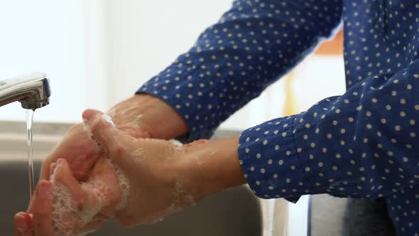 Caucasian woman washing her hands with soap at home