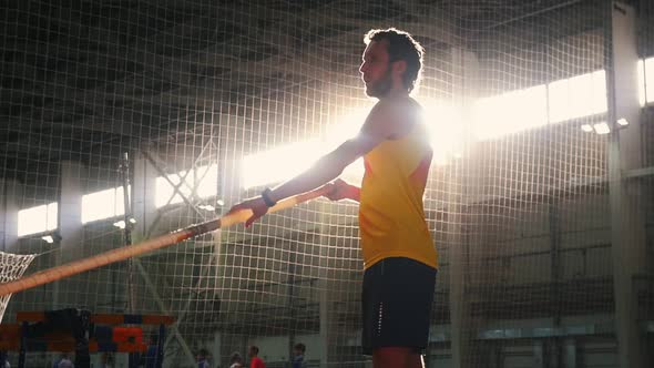 Pole Vaulting Indoors - a Man in Yellow Shirt Standing on the Track with a Pole and Preparing for