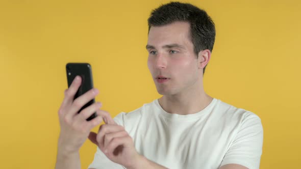 Shocked Man Using Smartphone, Yellow Background