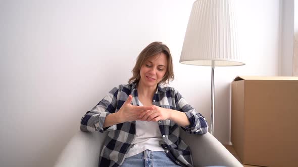 Portrait of a Young Confident Woman Sitting in an Armchair in Her First New Apartment Near Cardboard