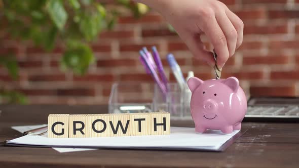 Table Wooden Cubes That Make Up the Word Growth Hand Puts Coins in a Piggy Bank