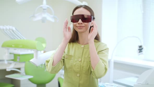 Young Woman Dressing Up UV Orange Safety Glasses. Portrait of Dentist