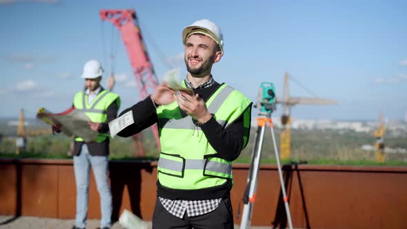 Medium Shot of Caucasian Man in Hard Hat Looking Up at Sunshine Scattering Money Smiling