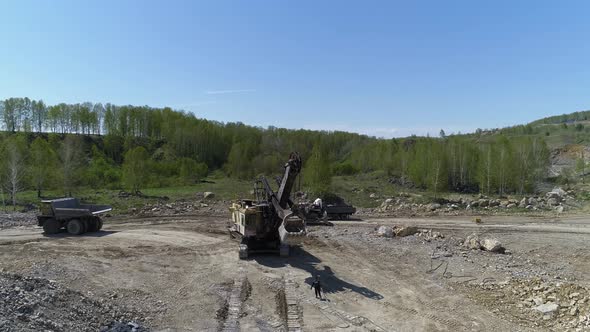 Excavator Loads Stones into a Dump Truck