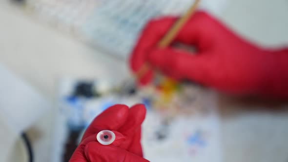 Anatomical model of eyeball. Close up of hands manufacturing eye prosthesis