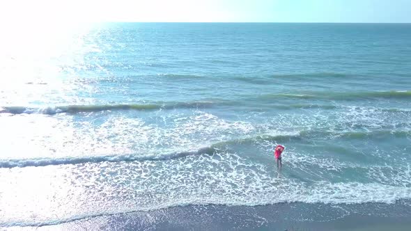 shooting from a drone, a woman enters the sea, and rejoices. happiness.