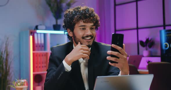 Businessman in Suit Enjoying Phone Video Chat while Overtime Working in Evening Office