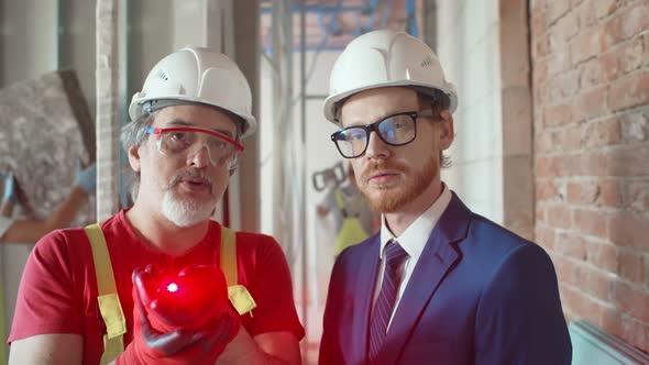 Businessman and Worker with Laser Level on the Building Site