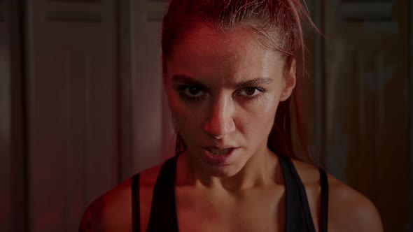 Athletic young woman with sweaty face screams furiously in anger after grueling workout