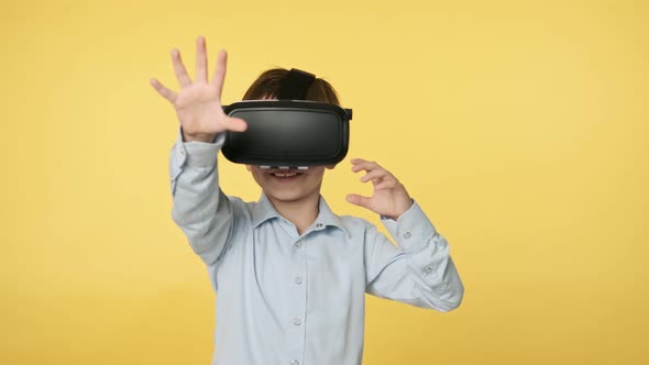 Little Boy in Virtual Reality Headset Standing in Studio and Looking Around