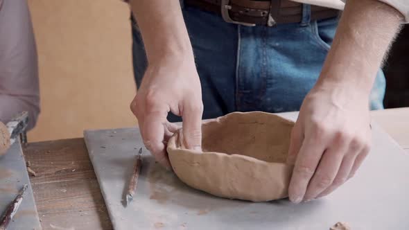 Small Child Girl with Adult Potter Man Working with Clay in Pott