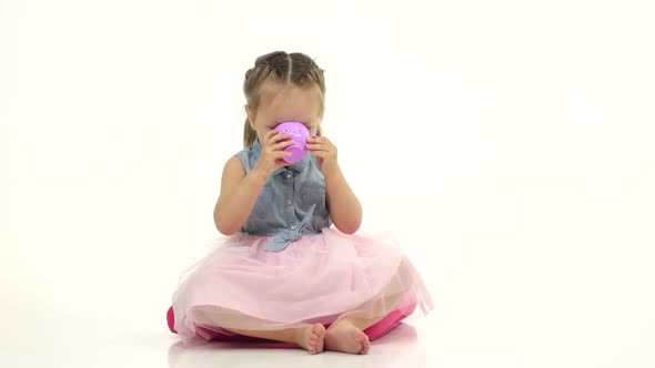 Child Sits on a Pillow and Drinks Tea. White Background. Slow Motion