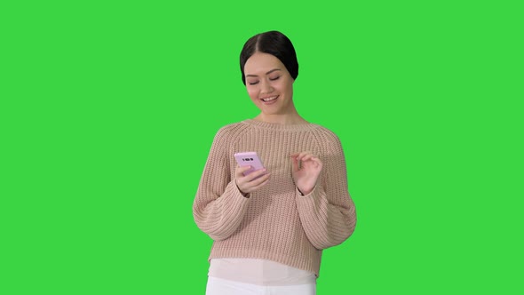 Smiling Young Female Texting on Her Mobile Phone and Laughing on a Green Screen, Chroma Key