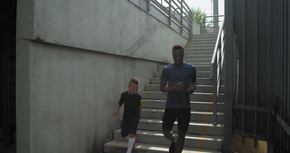 Diverse Father and Son Running on Concrete Staircase Together