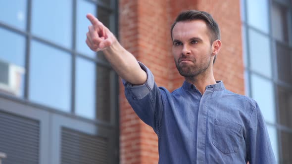 Casual Man Pointing with Finger Outside Office