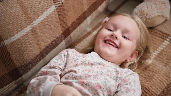 Portraits of an Adorable Cute Girl Having Fun with Her Mom on Couch While Hanging Out Together at