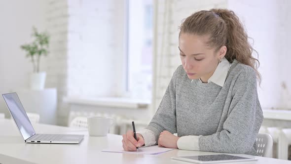 Young Latin Woman Doing Paperwork in Office