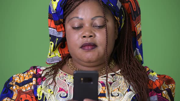 Overweight Beautiful African Woman Wearing Traditional Clothing Against Green Background