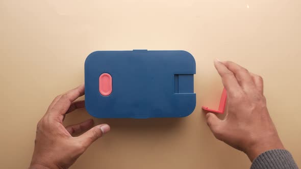 Young Man Open a Lunch Box on Table