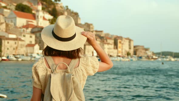 Attractive girl in hat looking the city from the pier