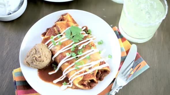 Dinner plate with Chicken enchiladas garnished with green onions and sour cream.