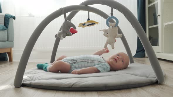 Cute Baby Boy Lying on Baby Activity Gym Play Mat Playing with Hanging Toys Infant Sensory