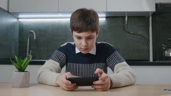 Portrait of Handsome Boy Playing Video Game with Smart Phone Indoors at Living Room