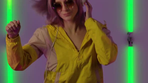 Portrait of Young Stylish Woman in Sunglasses and Big White Headphones Dances and Mixes Music at the