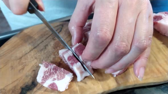 A woman cuts a large piece of pork meat with a knife. Meat with fat layers, pork neck. 4k