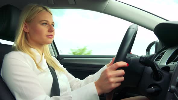 Young Attractive Blond Woman Drives a Car - Closeup
