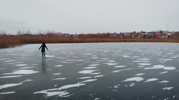 Aerial View. A Young Woman Is Skating on a Frozen Lake.