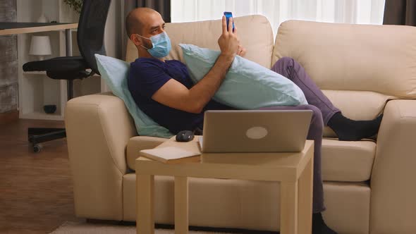 Man with Disposable Mask on Sofa