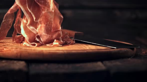 Super Slow Motion Sliced Into Thin Pieces of Ham Falls on a Cutting Board with a Knife