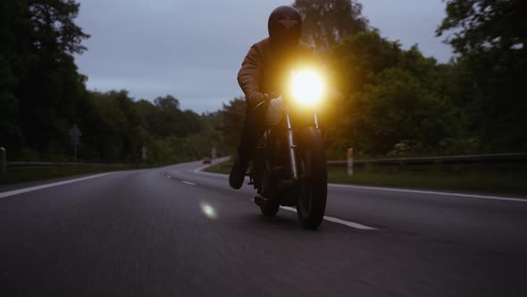 MotorcycleRiding Smoothly on a Narrow Road Under the Skies at Dusk alt