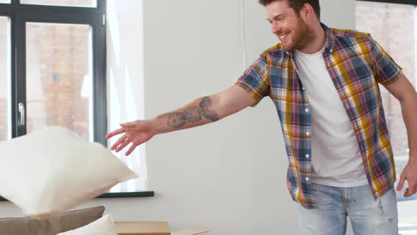 Man Dropping Pillows and Jumping To Sofa at Home