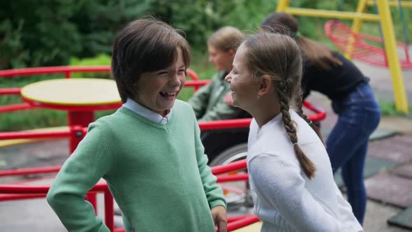 Caucasian Boy and Girl Mocking Laughing at Blurred Disabled Girl on Wheelchair at Background