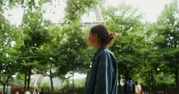 A Young Beautiful Woman Walks in the Park at the Foot of the Eiffel Tower