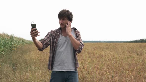 An agronomist in an agricultural field inspects the crop and talks via video link with partners.