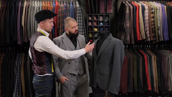 Slow motion of handsome man choosing a suit design with tailor in atelier